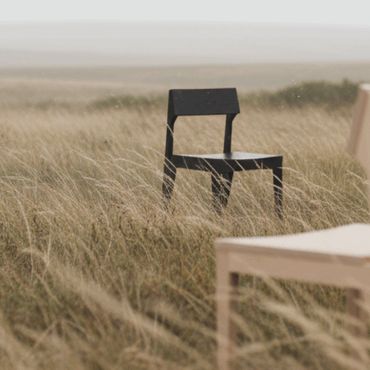 photorealistic_landscape_scene_of_three_chairs_positioned_in_a_vast_windswept_grassland