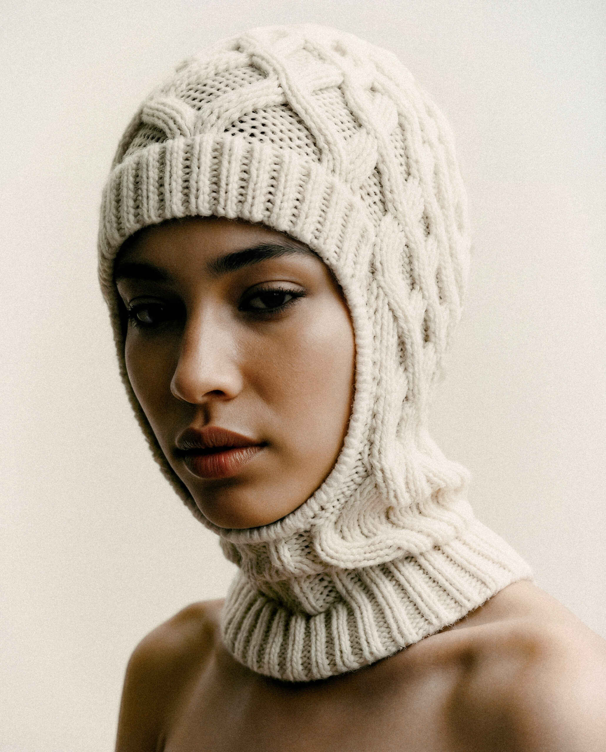 KI-produzierte Fashion-Kampagne: On-Model-Studioaufnahmen eines Strickaccessoires in monochromer Cream-Ästhetik.